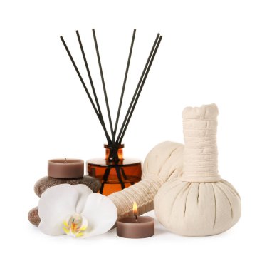 Beyaz arka planda yanan mum ve farklı bakım ürünleriyle güzel bir spa kompozisyonu