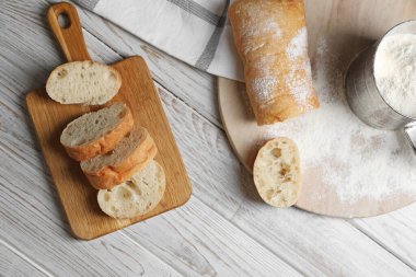 Fresh crispy ciabattas on white wooden table, flat lay