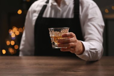 Barda elinde bir bardak viski olan barmen, yakın plan.