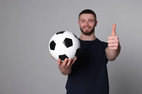 一个体格健壮的年轻人 他的足球在浅灰的背景下呈大拇指状 — 图库照片