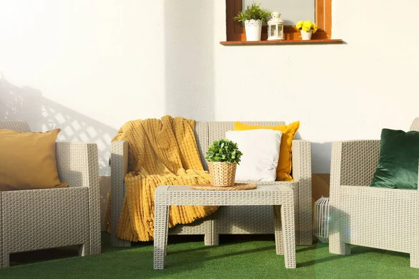 stock image Beautiful rattan garden furniture, soft pillows, blanket and houseplant outdoors