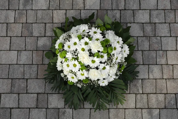 Funeral wreath of flowers on stone surface, top view
