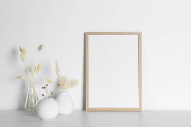 Boş fotoğraf çerçevesi ve beyaz masa üzerinde kuru dekoratif çiviler olan vazolar. Tasarım için model