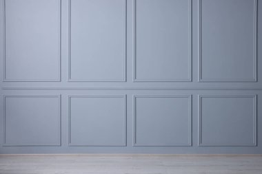 Açık mavi duvarı ve ahşap zemini olan boş bir oda.