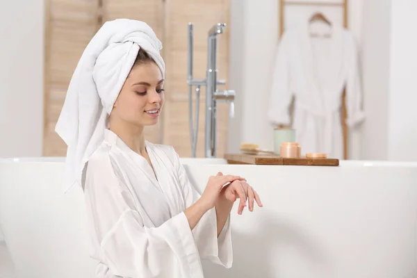 美しいです女性でホワイトローブ適用クリーム近く浴槽でバスルーム — ストック写真