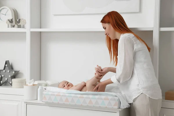 stock image Mother changing her baby's diaper on table at home