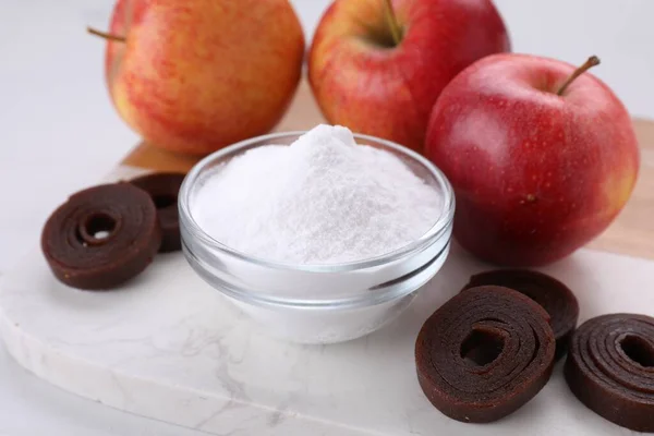 Sweet fructose powder, fruit leather rolls and apples on white table, closeup
