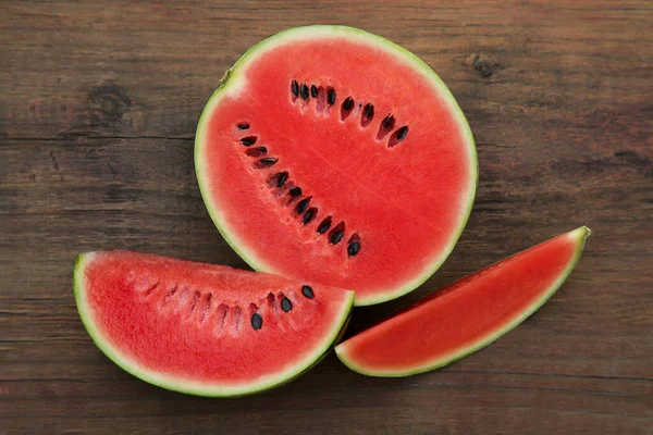 stock image Delicious cut watermelons on wooden table, flat lay