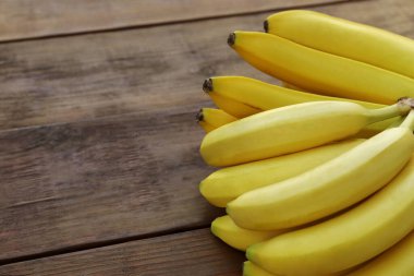 Ripe yellow bananas on wooden table, closeup. Space for text