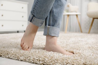 Evdeki yumuşak halıda duran kadın, yakın plan.
