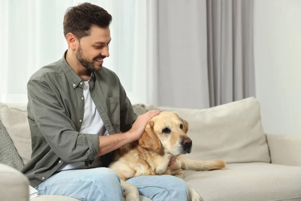 Gelukkige Man Zit Bank Met Zijn Schattige Labrador Retriever Thuis — Stockfoto