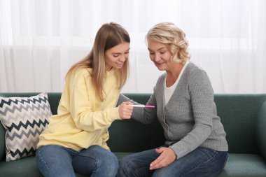 Genç bir kadın annesinin hamilelik testini evde gösteriyor. Müstakbel toruna büyük baba tepkisi