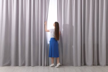 Kadın evde şık perdeler açıyor, arka manzara...