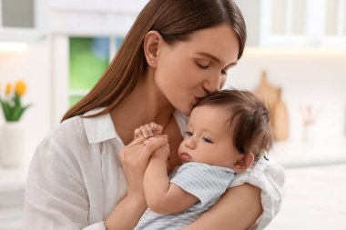 Mutfakta bebeğini öpen mutlu bir anne.