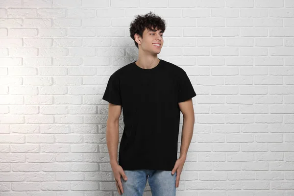 白いレンガの壁の近くに黒いTシャツを着た男 デザインのためのモックアップ — ストック写真