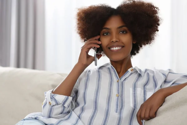 Smiling African American woman talking on smartphone at home. Space for text