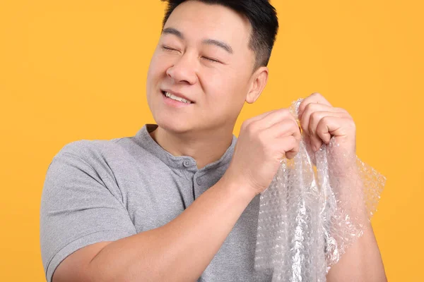 Gelukkig Aziatische Man Met Bubble Wrap Oranje Achtergrond — Stockfoto