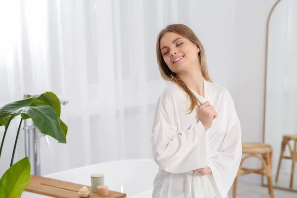 美しいです幸せな女性身に着けていますスタイリッシュな白いローブでライトバスルーム — ストック写真