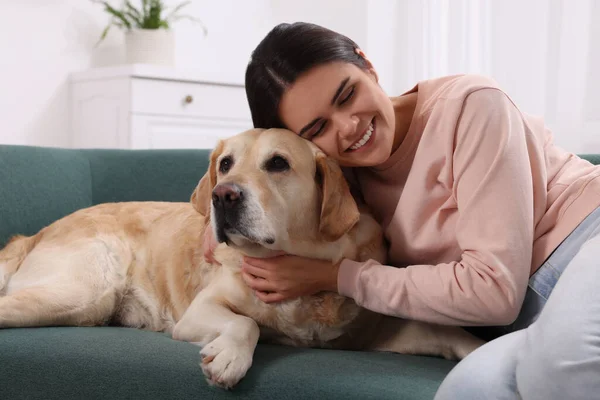 快乐的女人和可爱的拉布拉多猎犬在家里的沙发上 — 图库照片
