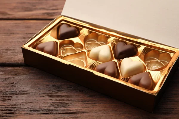 Partially empty box of chocolate candies on wooden table