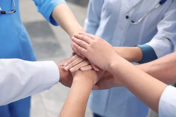 stock image Team of medical doctors putting hands together indoors, closeup