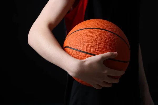 黒の背景にバスケットボールボールを持つ男の子 クローズアップ — ストック写真