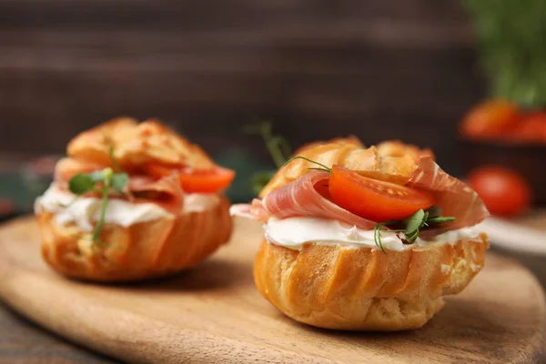 stock image Delicious profiteroles with cream cheese, jamon and tomato on table, closeup