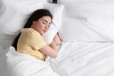 Güzel genç kadın yumuşak yatakta uyuyor.