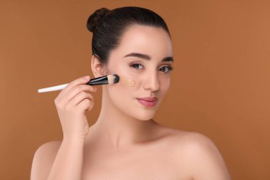 Esmer arkaplan üzerinde fırçayla temel uygulayan kadın