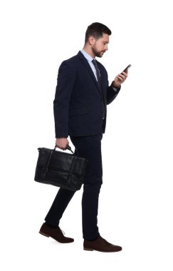 Akıllı telefon ve beyaz arka planda evrak çantası olan takım elbiseli yakışıklı bir iş adamı.