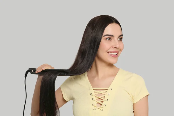 Beautiful Happy Woman Using Hair Iron Light Grey Background — Stock Photo, Image
