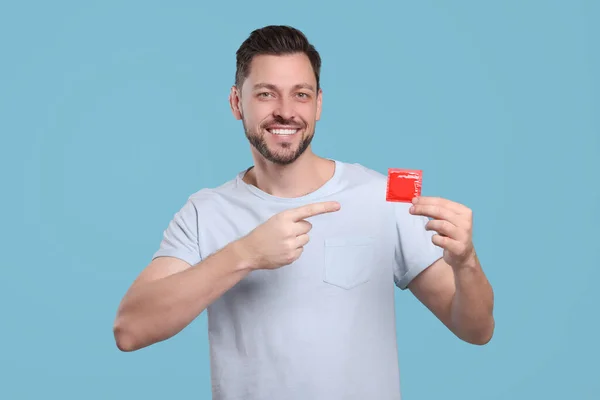 Homem Feliz Segurando Preservativo Fundo Azul Claro — Fotografia de Stock