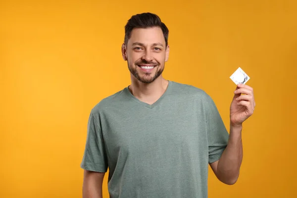 Homem Feliz Segurando Preservativo Fundo Laranja — Fotografia de Stock