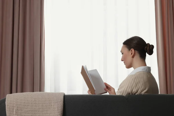 Kadın Pencerenin Yanındaki Kanepede Kitap Okuyor Evinde Şık Perdeler Var — Stok fotoğraf
