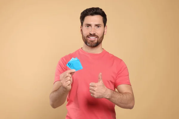Homem Feliz Com Preservativos Mostrar Polegar Fundo Bege Sexo Seguro — Fotografia de Stock