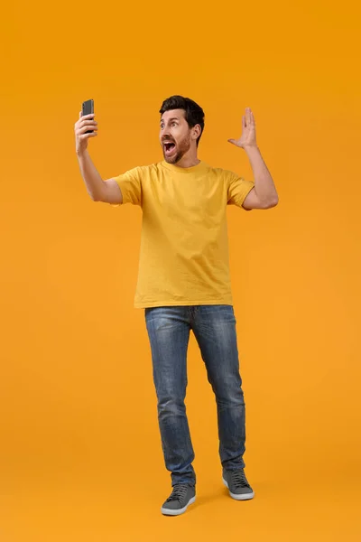 感情的な男取ります自撮りとともにスマートフォン上の黄色の背景 — ストック写真