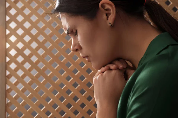 Upset woman listening to priest during confession in booth