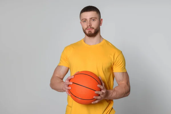 Açık Gri Arka Planda Basketbol Topu Olan Atletik Genç Adam — Stok fotoğraf