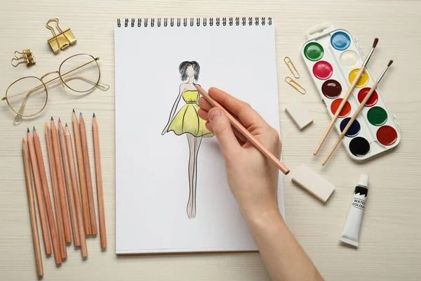 时装设计师创造新的外观 妇女用铅笔在白色木制桌子的垫子上画草图 — 图库照片