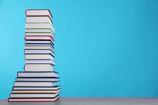 Stack of hardcover books on light blue background. Space for text