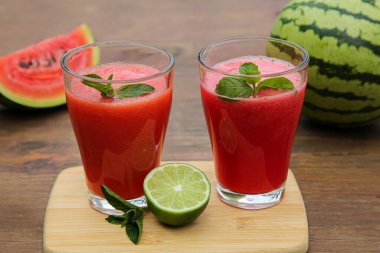 Bardaklar dolusu nefis karpuz püresi. Nane ve kireç ile ahşap masada.