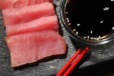 Lezzetli sashimi (taze çiğ ton balığı parçaları) ve siyah tabakta soya sosu, düz konum