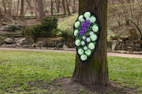 Funeral wreath of flowers on tree outdoors