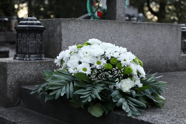 Funeral wreath of flowers on granite tombstone in cemetery