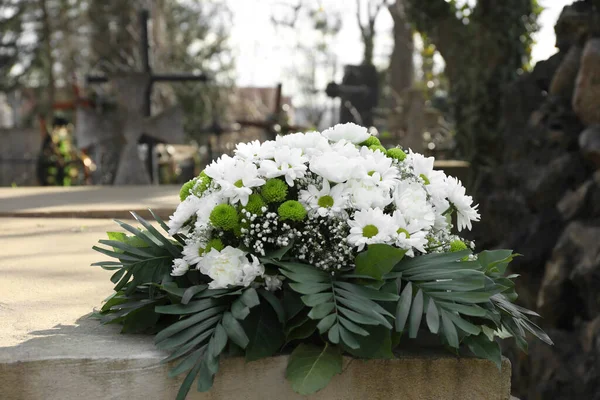 Funeral wreath of flowers on tombstone in cemetery