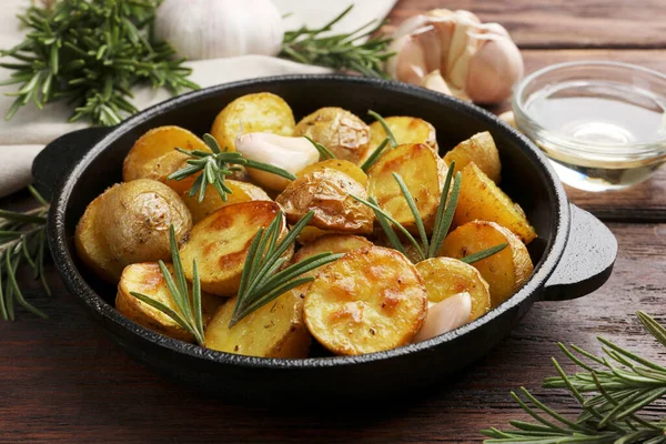 美味的烤土豆 有迷迭香 放在木制桌子上的煎锅里 — 图库照片