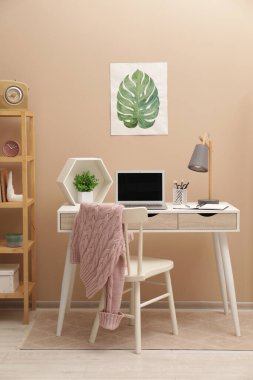 Modern dizüstü bilgisayarı olan rahat bir iş yeri ve evde rahat bir sandalye.