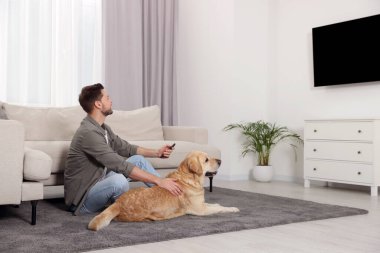 Evindeki şirin Labrador Retriever 'ının yanında televizyonu açan bir adam. Metin için boşluk
