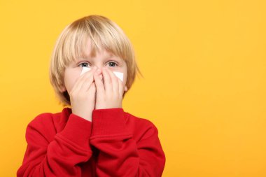 Çocuk burnu turuncu arka planda sümkürdü, mesaj için yer açtı. Soğuk belirtileri