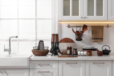 Mutfaktaki mutfak tezgahında farklı mutfak aletleri ve tabaklar var.